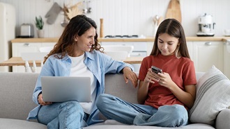 Moeder en dochter met laptop en gsm